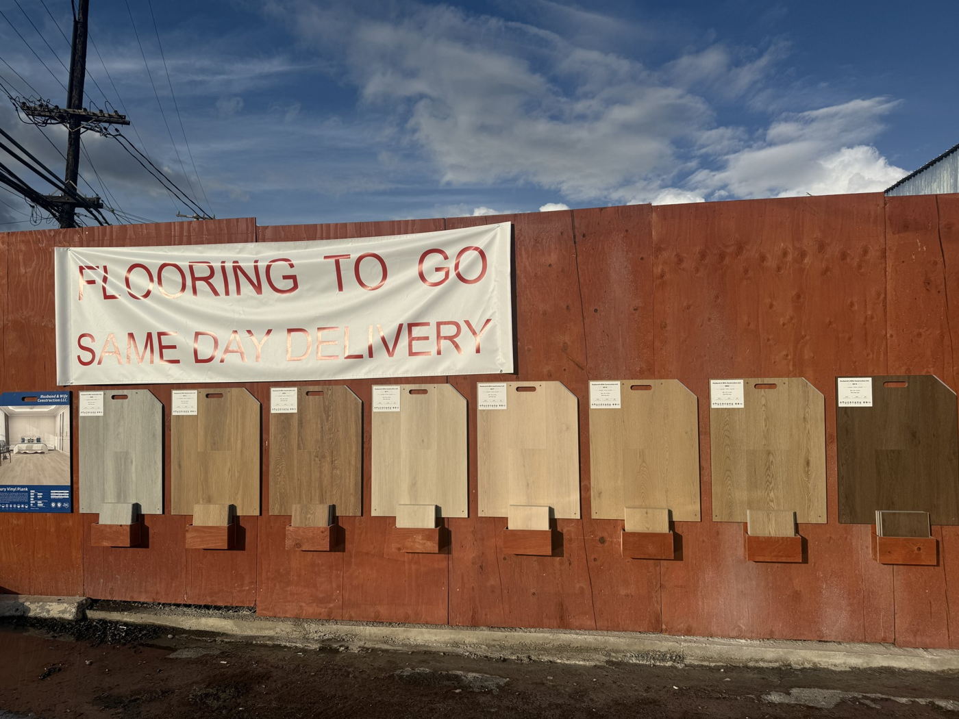 板材尺寸 samples hanging on the rust-red container wall outside the Māpunapuna showroom, under a banner reading 地板 To Go, Same Day Delivery